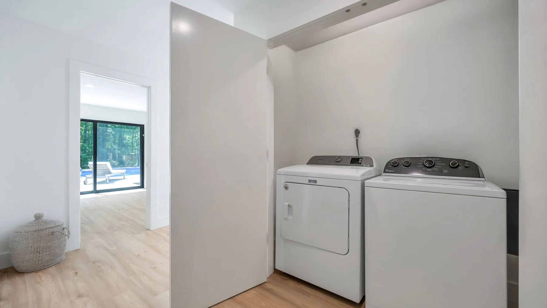 A laundry room with a washer and dryer beside an open doorway.