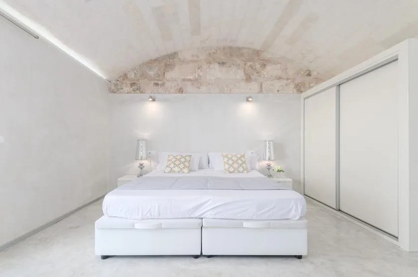 Un dormitorio luminoso con una cama grande y puertas corredizas blancas de armario.