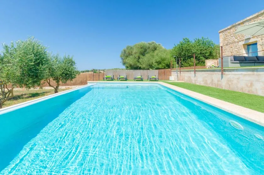 Una piscina al aire libre está junto a un jardín y un edificio de piedra.