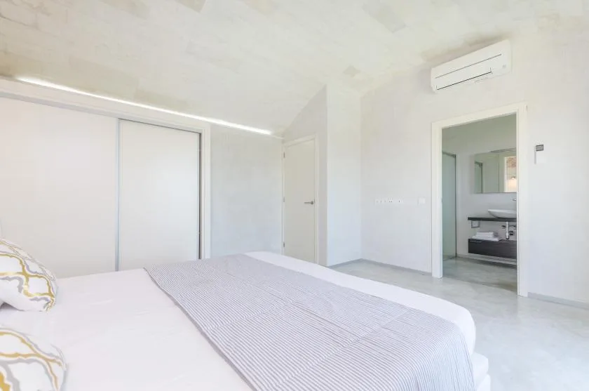 Un dormitorio luminoso con una cama y una puerta abierta al baño.