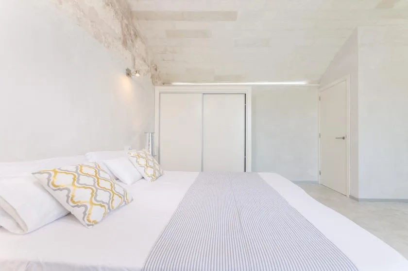 Un dormitorio luminoso con una cama bien hecha y ropa de cama clara.