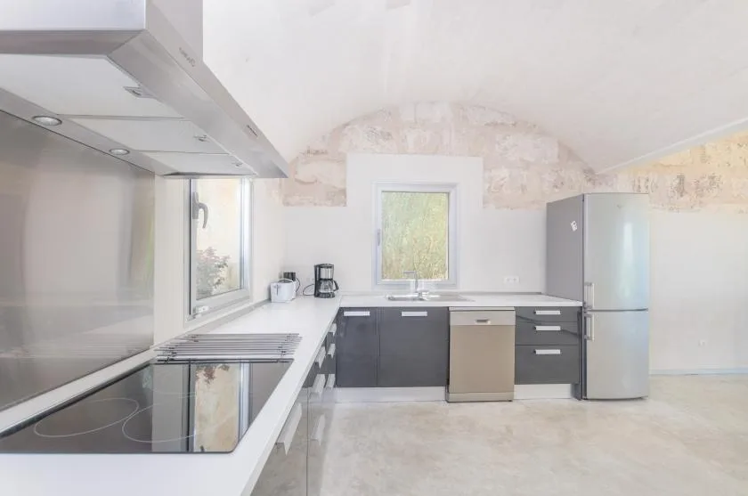 Una cocina luminosa con gabinetes oscuros, una encimera y un refrigerador.