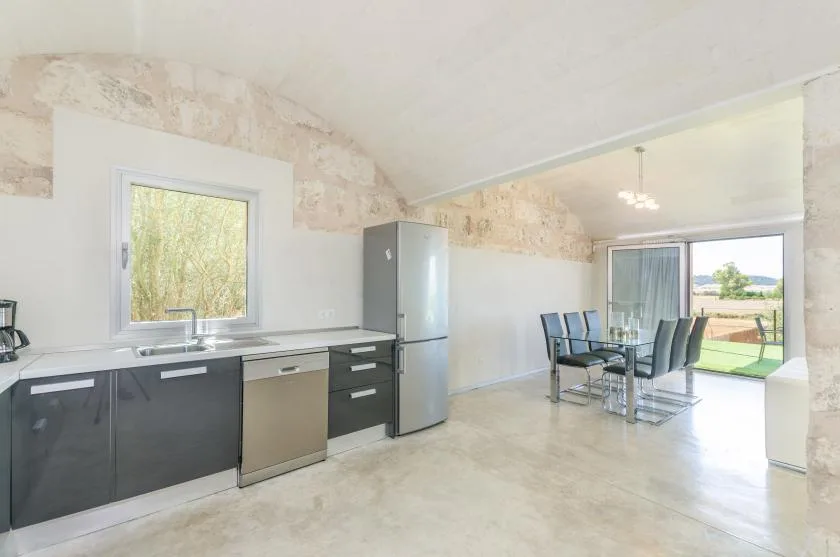Una cocina luminosa y zona de comedor se abren a un patio mediante grandes puertas de vidrio.