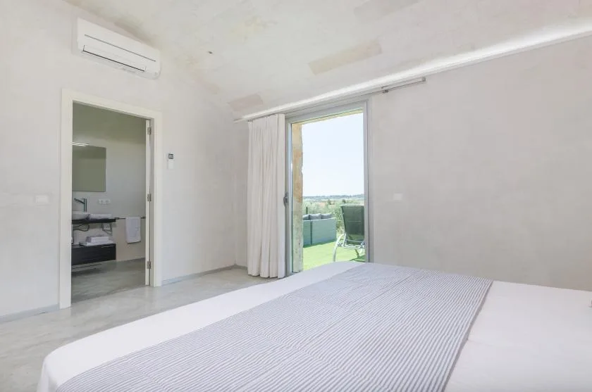 Un dormitorio luminoso da a una terraza a través de una puerta corrediza de vidrio.