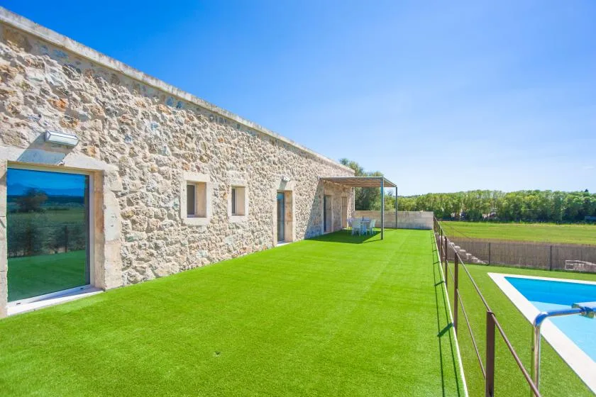 Un edificio de piedra da a un césped verde y una piscina al aire libre.