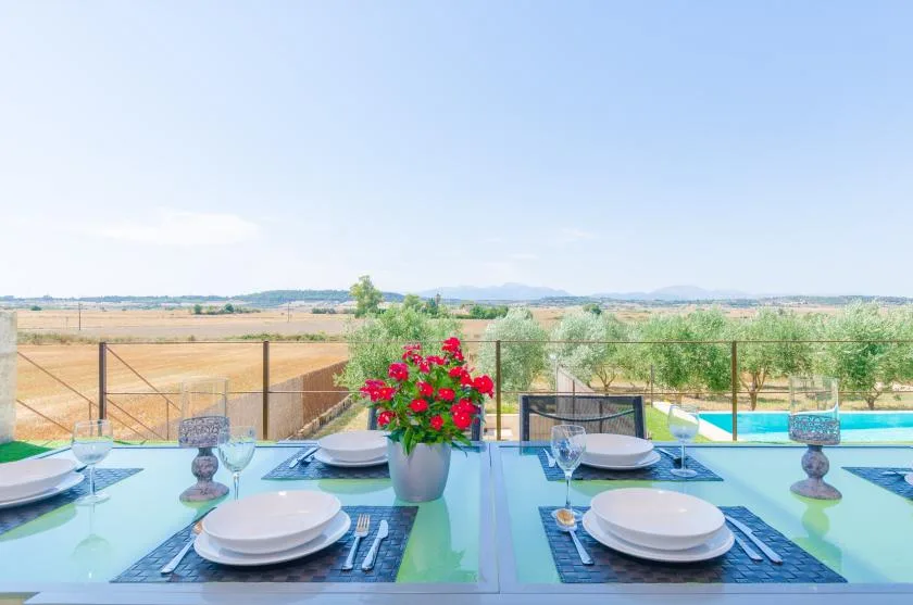 Una mesa preparada para comer da a una piscina y al campo abierto.