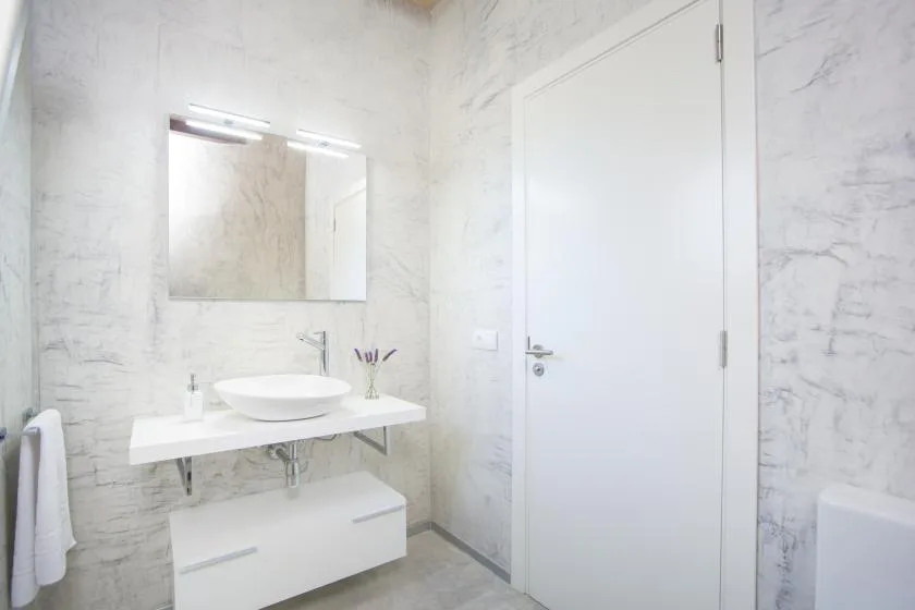 Un baño luminoso con lavabo suspendido y espejo.