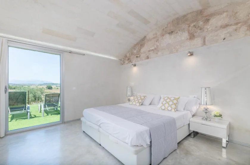 Un dormitorio con una cama grande y puertas de vidrio que dan a un césped.