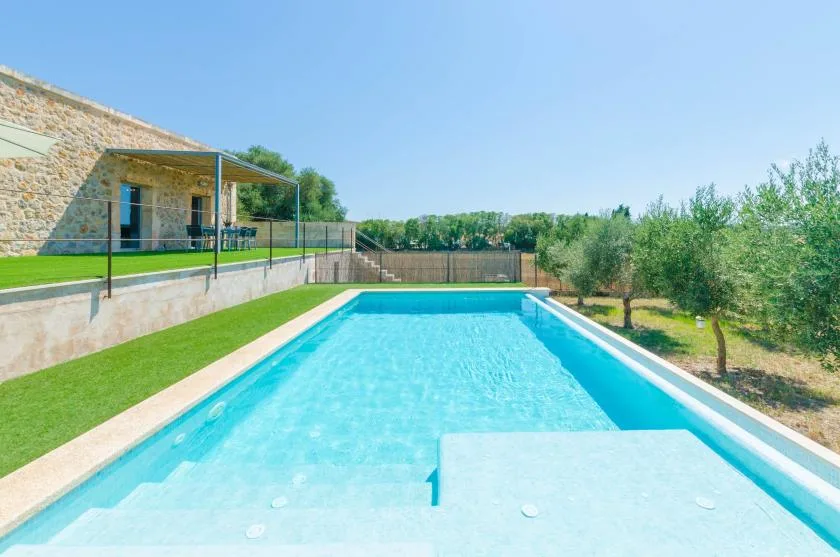 Una piscina al aire libre con un edificio de piedra y vegetación alrededor.