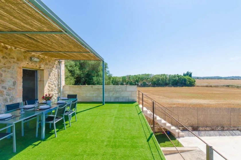 Una terraza exterior cubierta con comedor da a campos abiertos.
