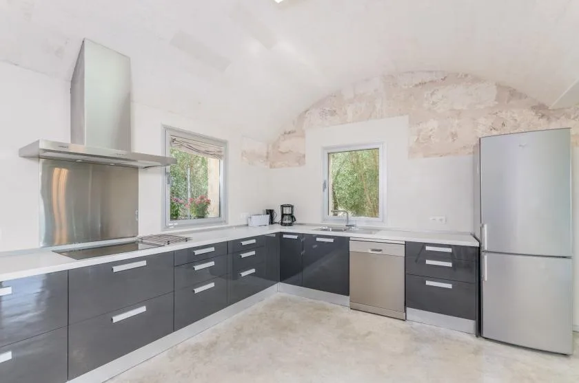 Una cocina luminosa con gabinetes oscuros, electrodomésticos de acero inoxidable y ventanas con vista al verdor.