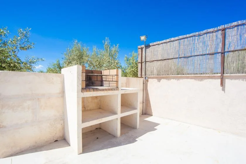 Un patio exterior soleado con una encimera empotrada y muros altos alrededor.