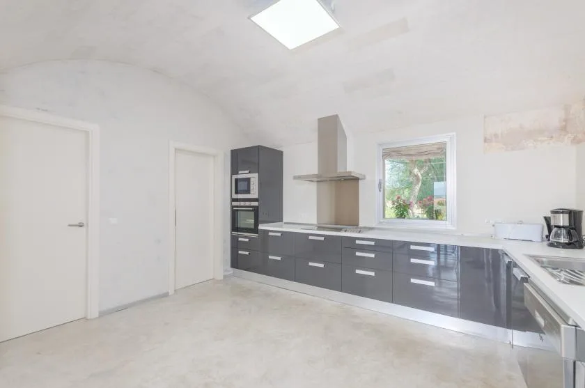 Una cocina luminosa con gabinetes oscuros y una ventana sobre la encimera.