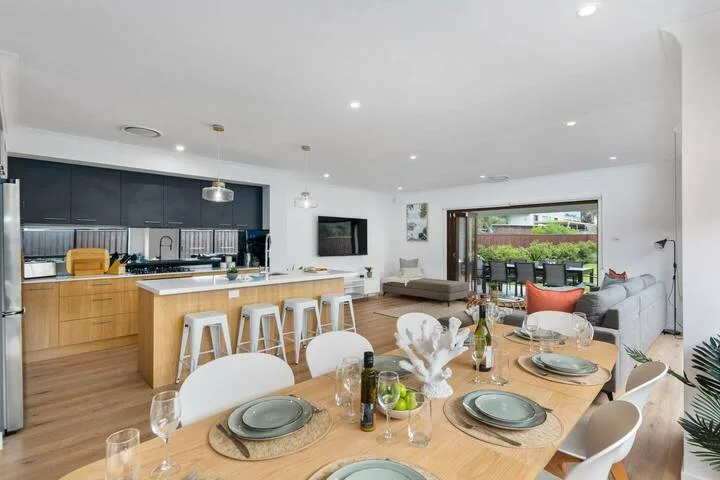 Un comedor y cocina de planta abierta con la mesa puesta y asientos.