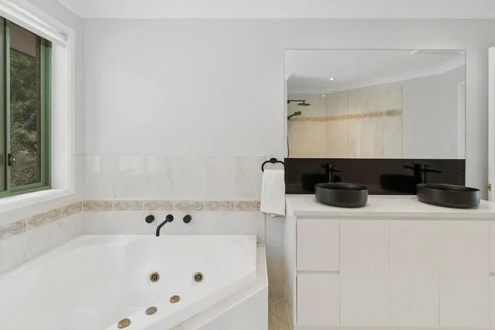 Un baño luminoso con bañera, tocador con espejo y dos lavabos.