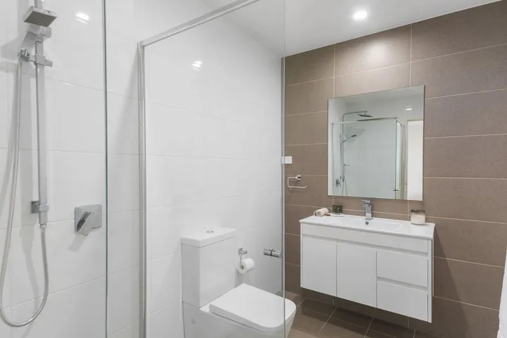 Un baño moderno con ducha de vidrio, inodoro y lavabo.
