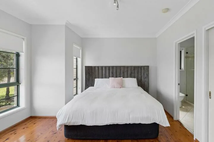Un dormitorio luminoso con una cama y ventanas grandes.