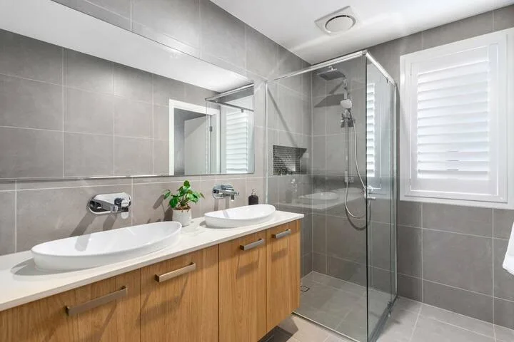 Un baño moderno con un tocador largo, espejo y ducha de vidrio.