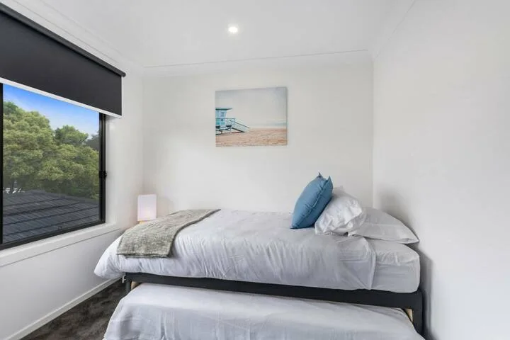 Un dormitorio luminoso con una cama tendida junto a una ventana grande.