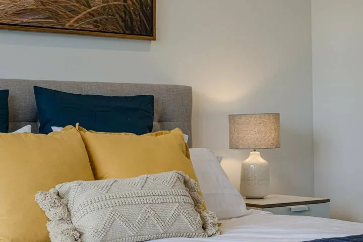 Dormitorio con una cama con almohadas amarillas junto a una lámpara de noche.