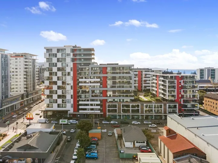 Edificios de apartamentos modernos dan a un estacionamiento bajo un cielo azul.