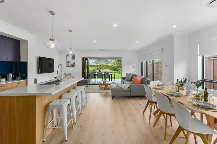 Sala y comedor de planta abierta con isla de cocina y asientos junto a grandes ventanales.