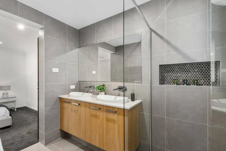Un baño alicatado cuenta con un mueble largo con dos lavabos y una ducha de vidrio.