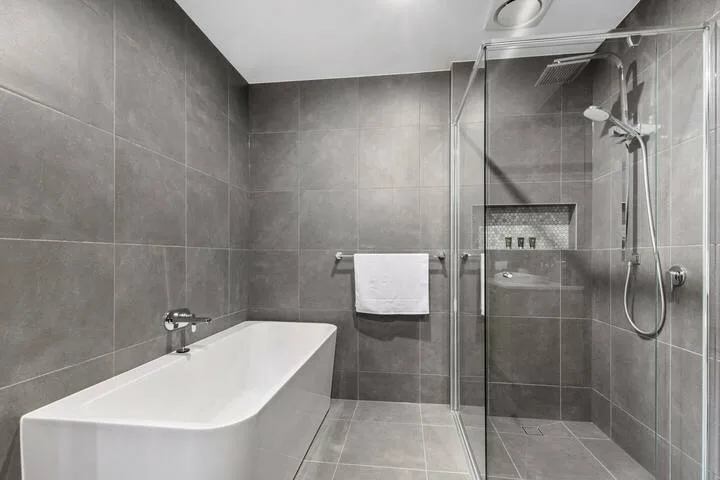 Un baño moderno con bañera y ducha con mampara de vidrio.