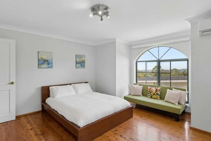 Un dormitorio con una cama junto a una gran ventana arqueada y asientos.
