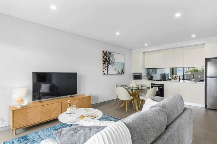 Una sala luminosa da a la cocina, con un televisor y una mesa de comedor a la vista.