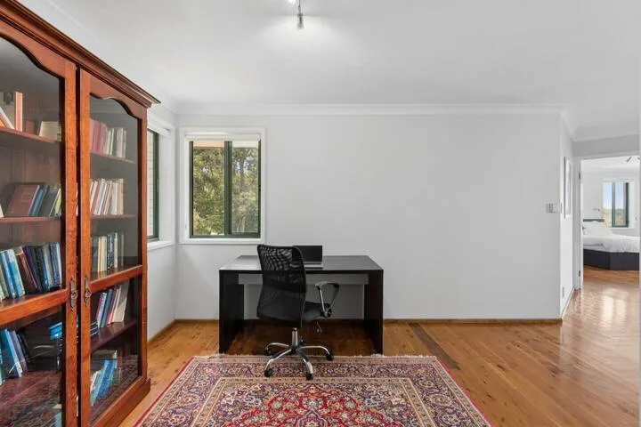 Una zona de estudio con escritorio y estantería junto a una ventana.