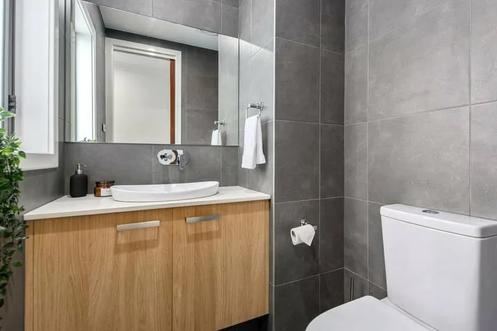 Un baño moderno con mueble de madera, lavabo e inodoro.