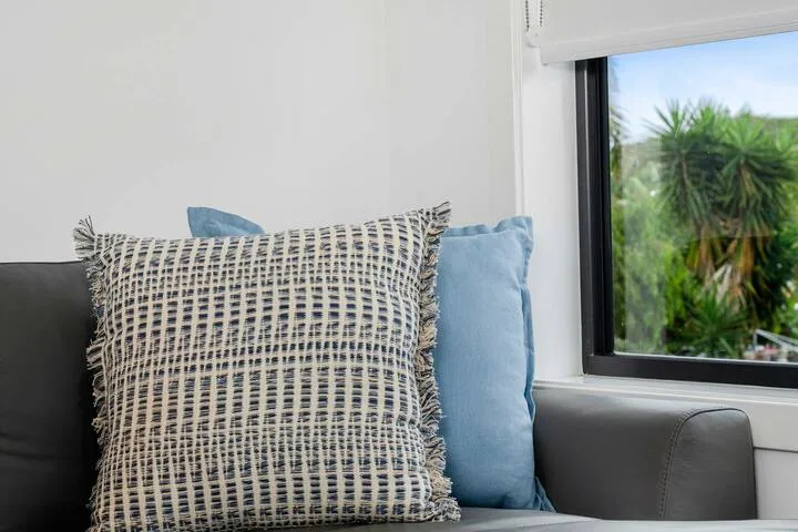 Una zona de asientos junto a una ventana, con cojines estampados y azules.