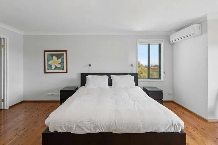 Un dormitorio con una cama grande, mesitas de noche y una ventana.