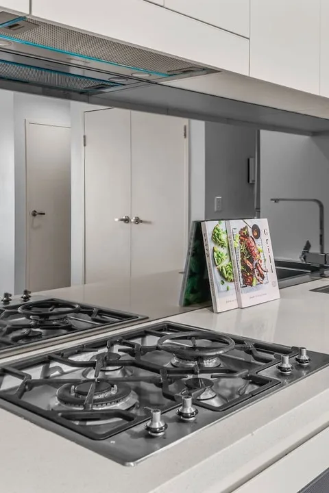 Una cocina moderna con una placa de gas de acero inoxidable y armarios blancos.