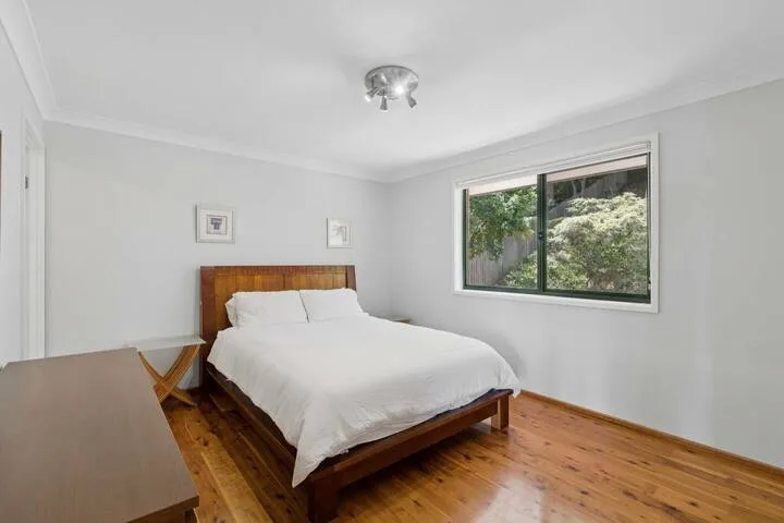 Un dormitorio con una cama junto a una ventana con vistas a la vegetación.