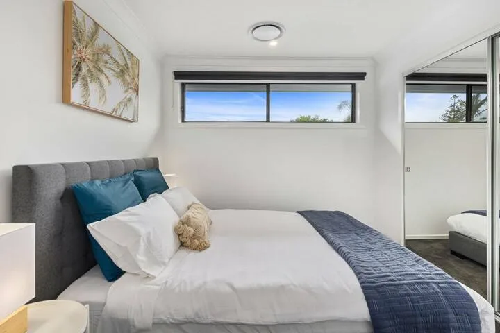 Un dormitorio con una cama arreglada y una ventana estrecha encima.