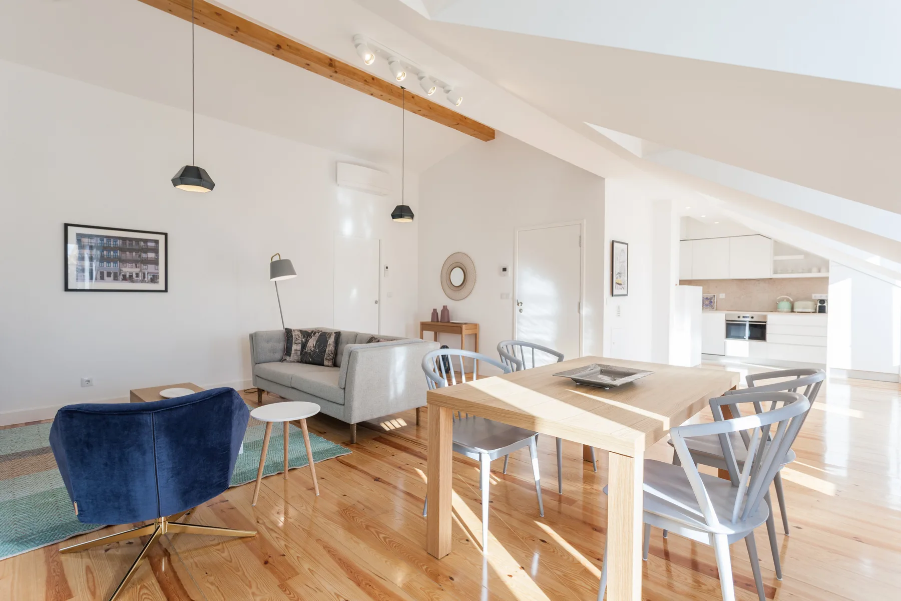 A bright open-plan living and dining area with seating and a wooden table.