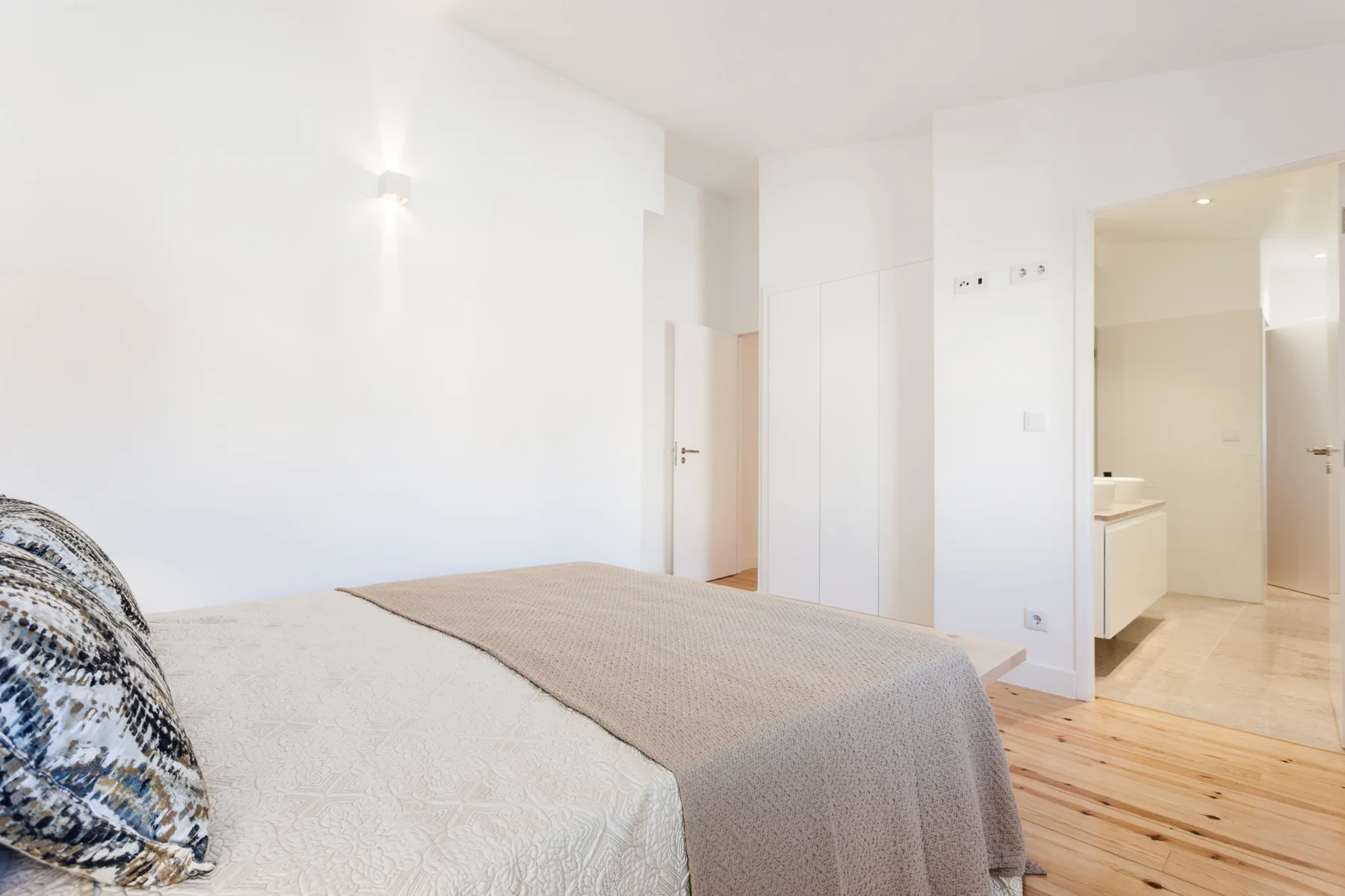 A bright bedroom with a bed and an adjoining bathroom.