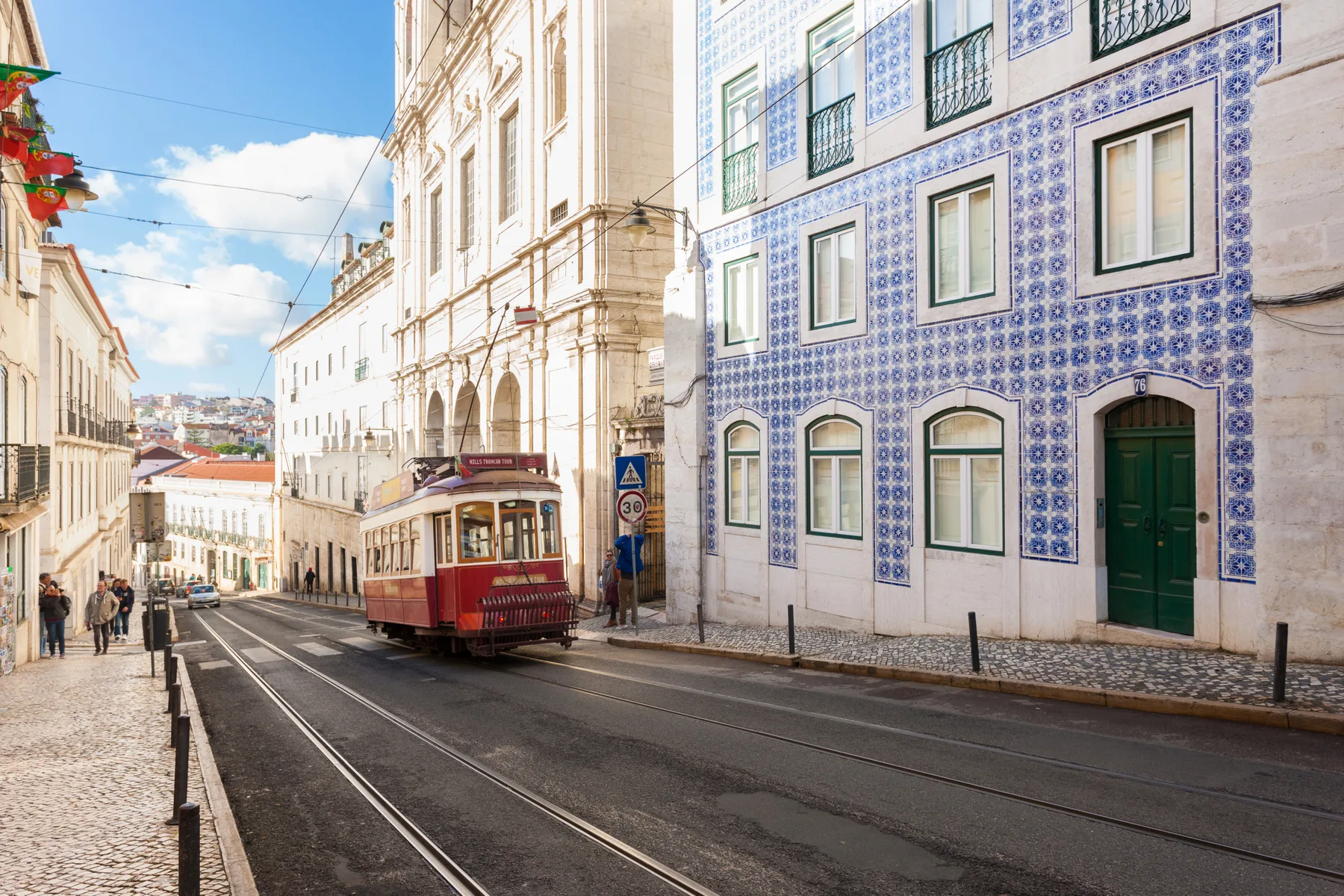 A city street with tram tracks runs between rows of buildings.