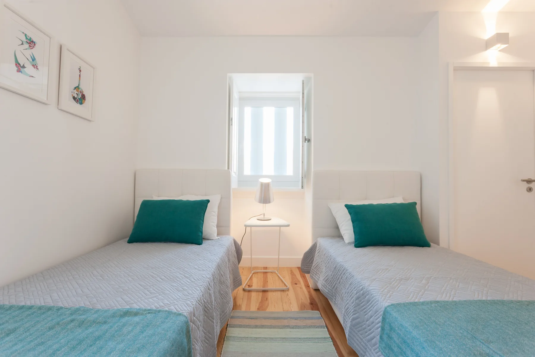 A bright bedroom with two single beds beside a window.