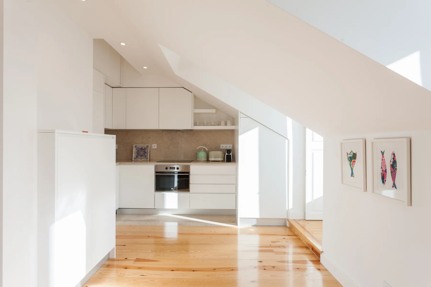 A bright kitchen with white cabinets and a wooden floor.