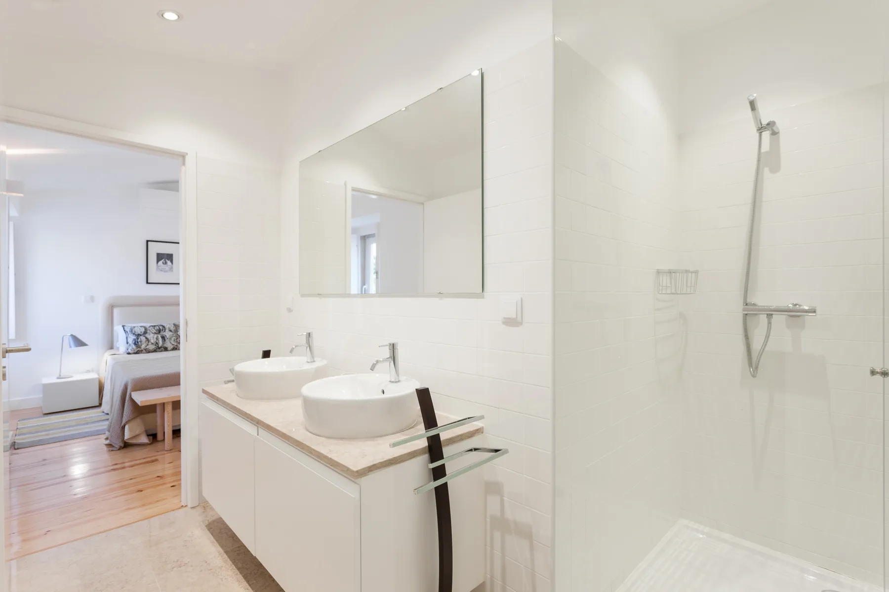 A bright bathroom with a double vanity, mirror, and shower.