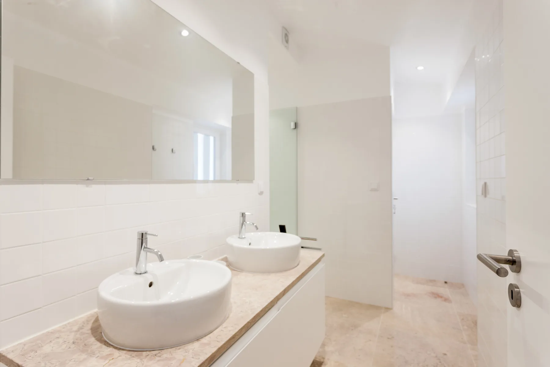 A bright bathroom with two sinks and a large wall mirror.