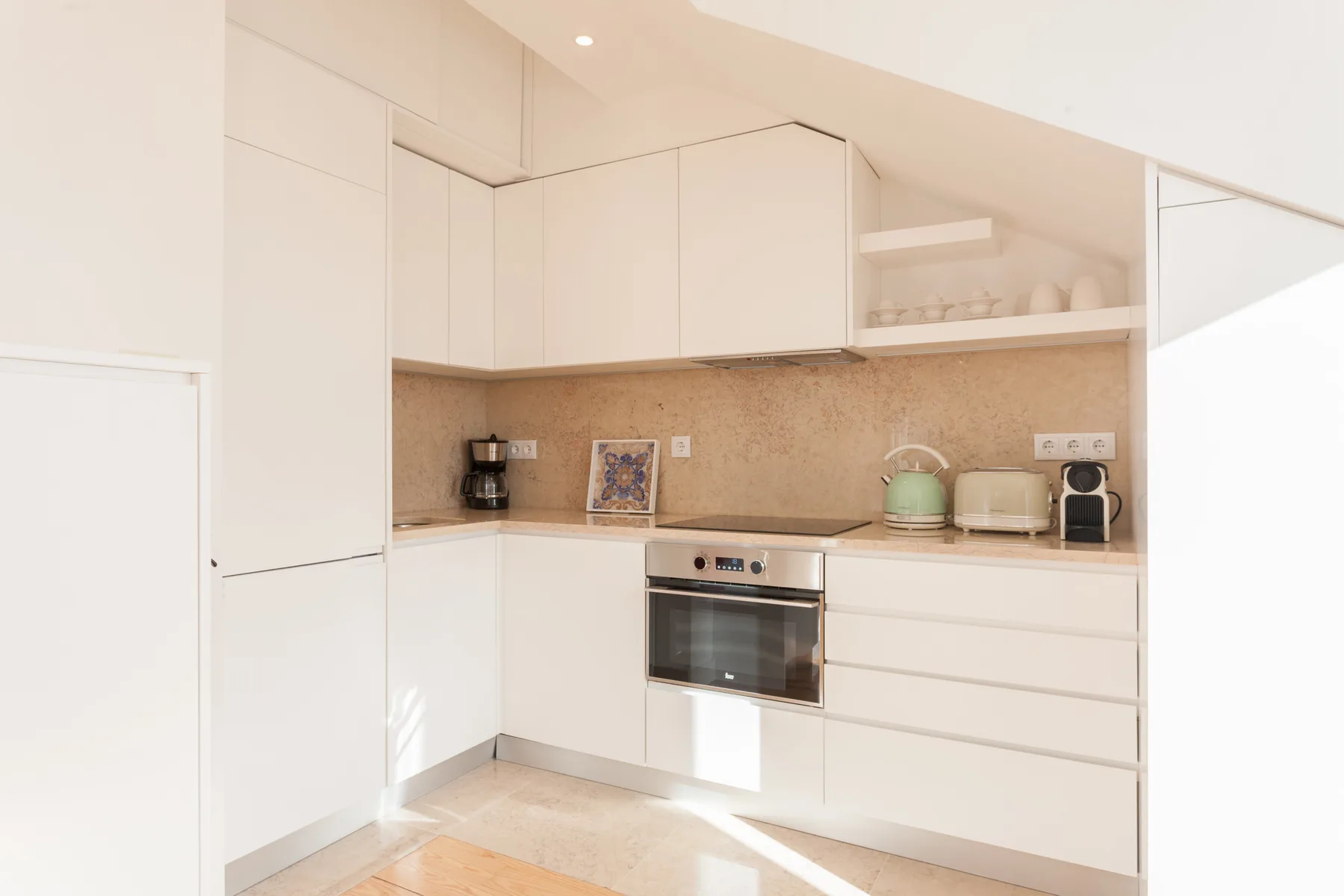 A bright kitchen with white cabinets, a countertop, and built-in appliances.