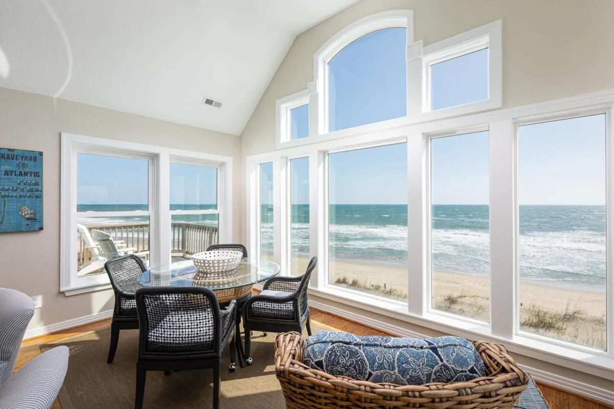 A bright dining area with large windows overlooking the ocean and beach.