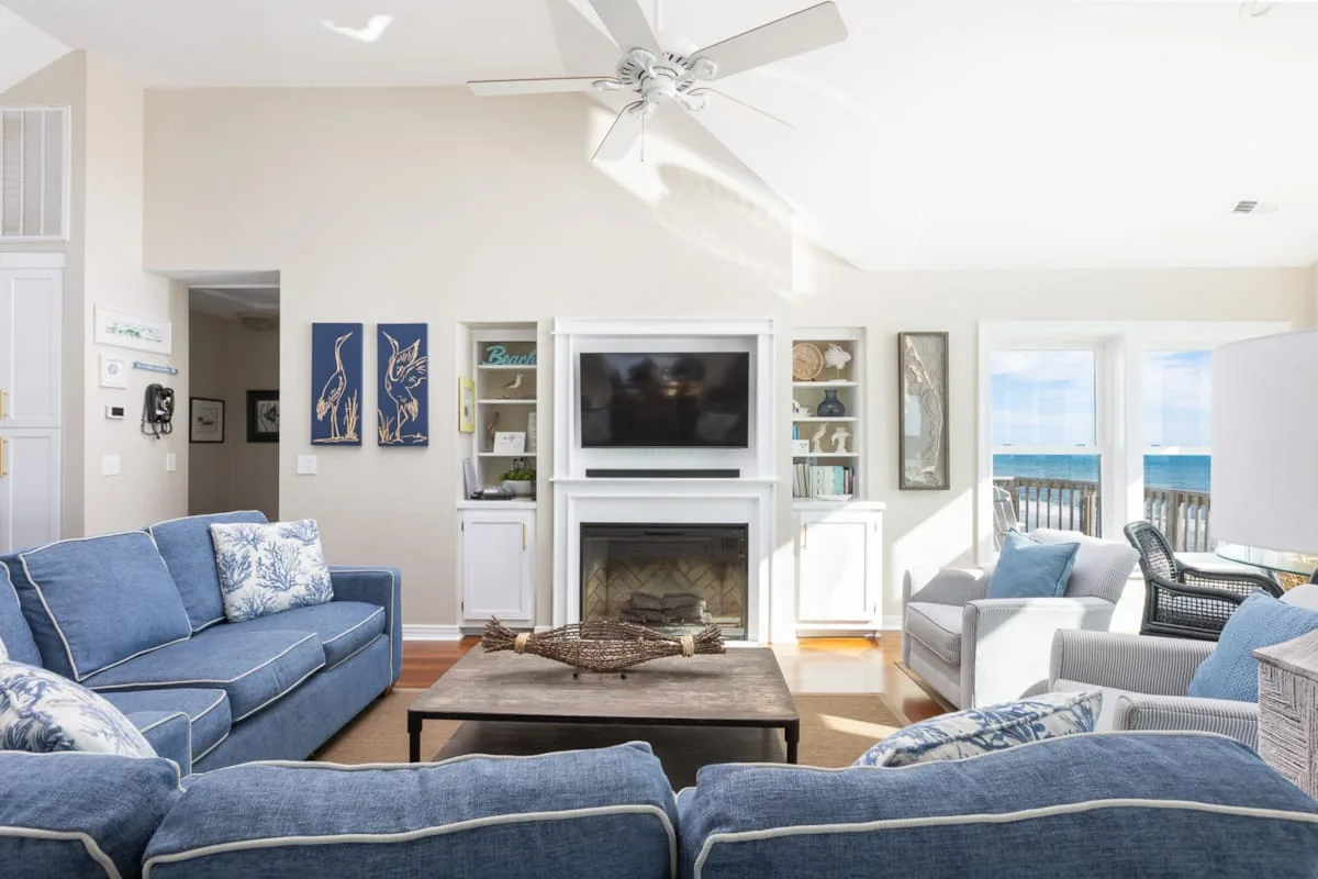 A bright living room with blue seating and a fireplace beneath a television.