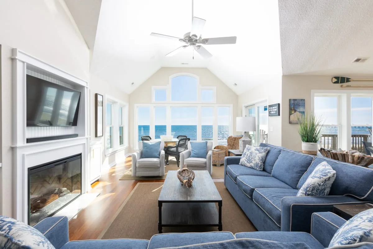 Una sala luminosa con asientos azules y grandes ventanas con vista al agua.