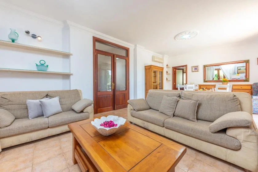 Una sala luminosa con asientos beige y una mesa de centro de madera.