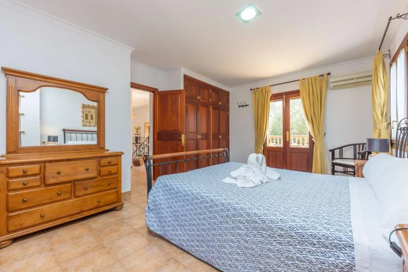 Un dormitorio con una cama grande, una cómoda de madera y cortinas amarillas junto a la ventana.